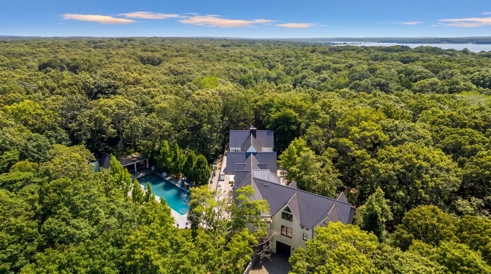 The house set into unbroken oak canopy with the bay on the horizon