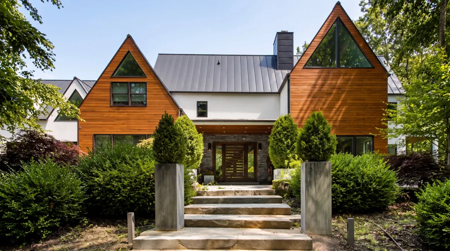 Cedar-clad gabled entry facade with stone steps and clipped topiary